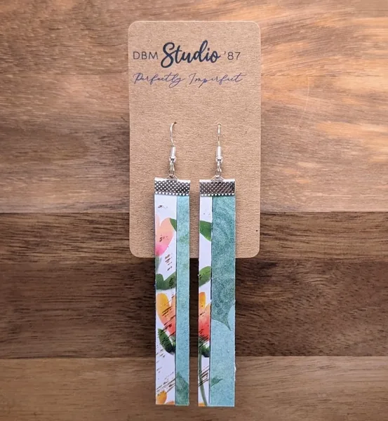 long split scrapbook paper and felt earrings. Half orange and green florals on white, the other half medium blue florals on blue. in silver finishes.